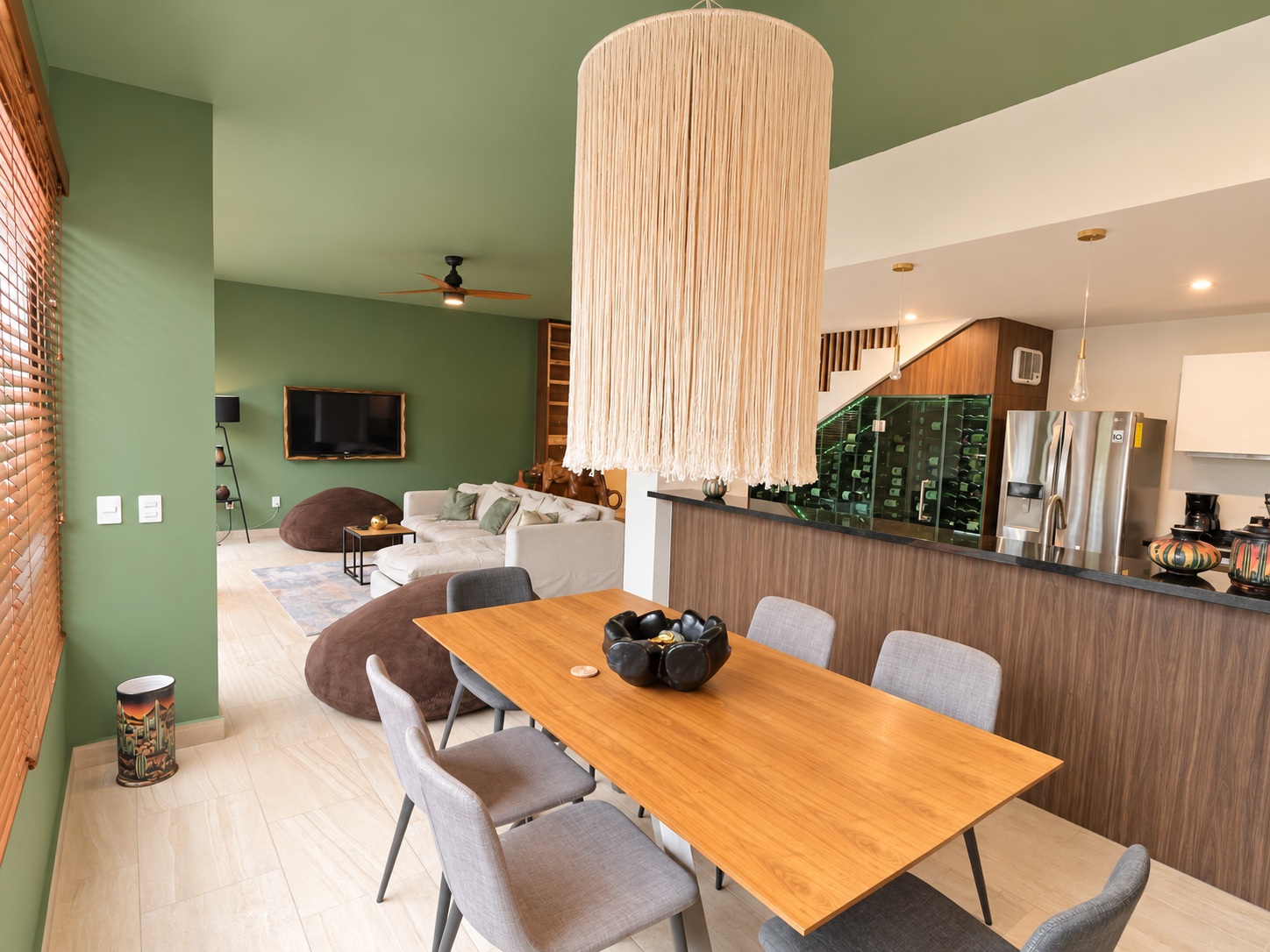 Dining room with large woven pendant light and glass wine cellar at Aleda C5 condo in Playa del Carmen